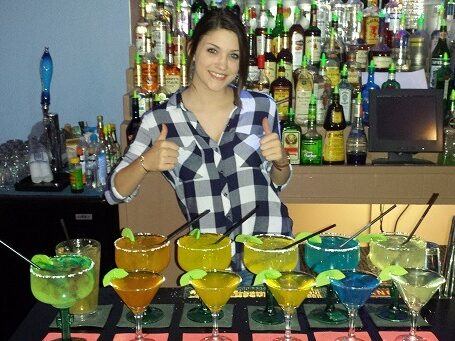 Student behind the bar showing finished cocktails